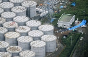 An aerial view shows workers wearing protective suits and masks working atop contaminated water storage tanks at TEPCO's tsunami-crippled Fukushima Daiichi nuclear power plant in Fukushima
