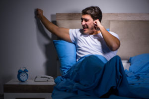 Young man struggling from noise in bed