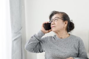 Asian senior woman make a phone call white sitting on sofa at ho