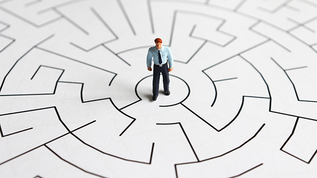 A Miniature Man Standing In The Middle Of A Maze.