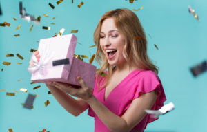 Cheerful girl opening gift box with interest