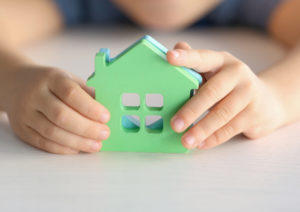 Child holding figures in shape of houses, closeup. Adoption conc
