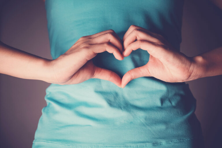 Woman hands making a heart shape on her stomach, healthy bowel d