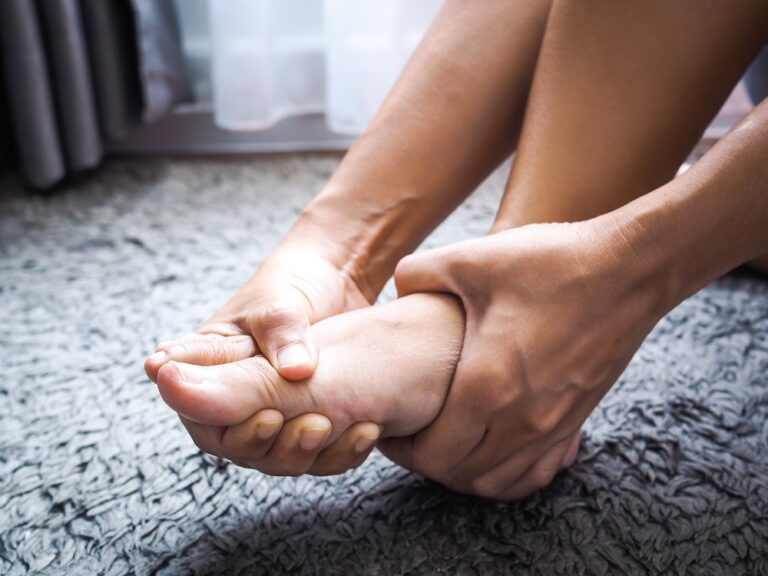 Women suffering from acute foot pain and use hands to massage on