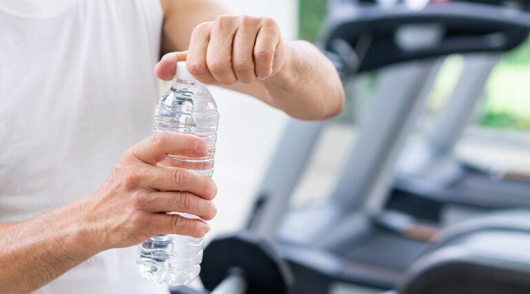 Senior man drink mineral water in fitness center.