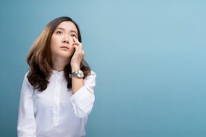 Woman has eyes pain isolated over blue background