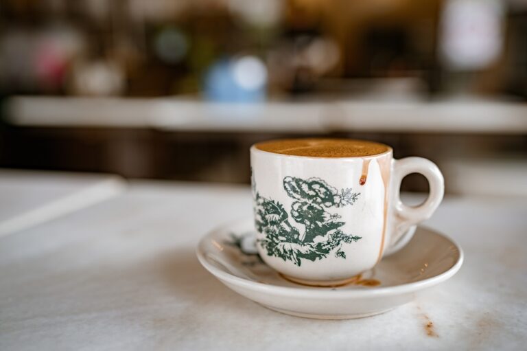 White coffee served in cup with saucer on white marble table