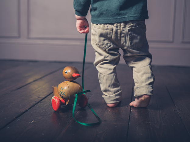 Little boy pulling a wooden duck