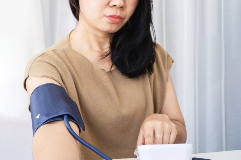 Asian woman self checking blood pressure with machine at home