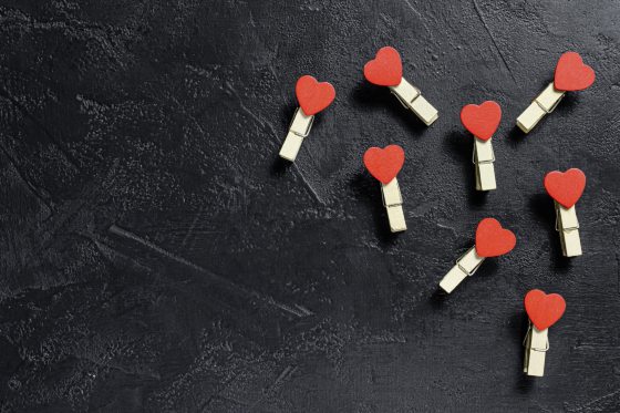 Valentines day concept. Red hearts and clothespins. Black background. Top view. Space for text