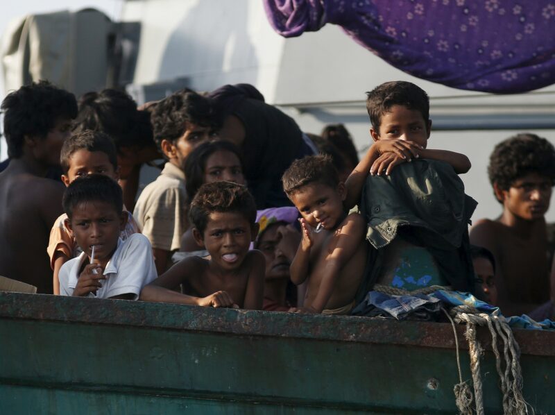 Migrants are seen aboard a boat tethered to a Thai navy vessel, in waters near Koh Lipe island