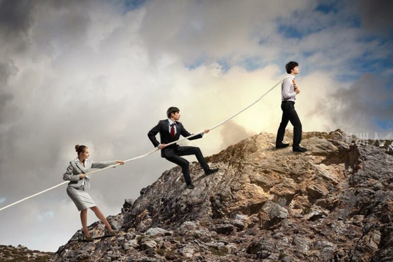 Image Of Three Businesspeople Pulling Rope Atop Of Mountain