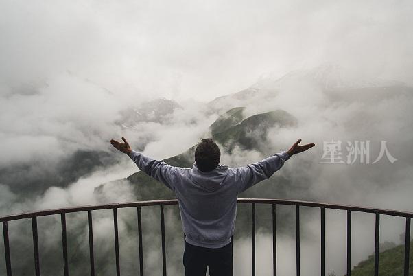 Young Traveler Man Wearing Hoodie Stands On The Viewpoint In National Park And Watching Outstanding Foggy Landscape. Beautiful Moment Miracle Of Nature