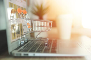 Online Shopping Concept, Shopping Cart With Blurry Laptop On The